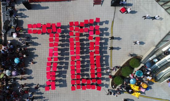 在《我和我的祖国》的背景音乐下，现场人群手持红色展示牌，组成“70”字样。