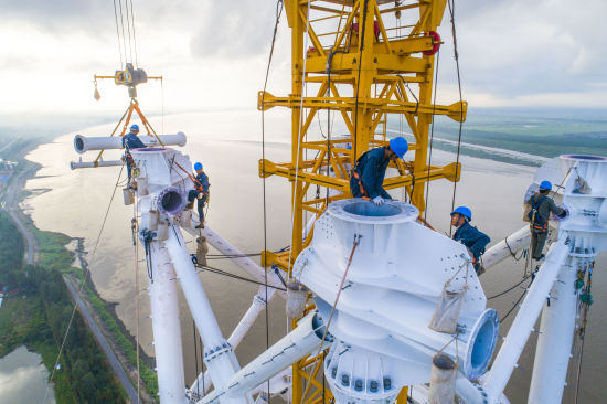 图：施工人员在近200米高空对跨越塔进行组立。