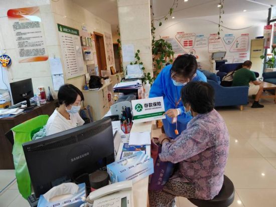 图：临港新片区支行员工在泥城镇云帆苑居委，为居民展示存款保险标识。