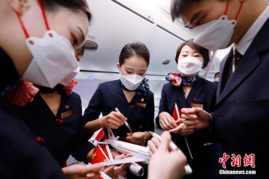 东航首架国产C919飞机抵达上海虹桥机场，乘务员在飞机模型上签名留念。 殷立勤 摄